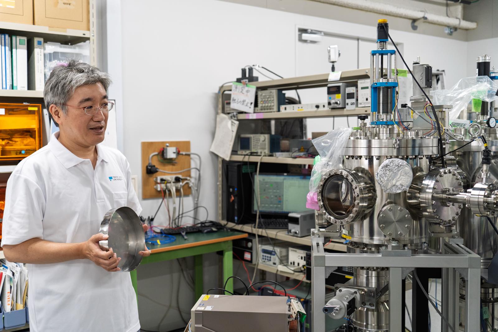 研究室にある電子物性測定装置を説明する三宅教授。この装置も三宅教授が設計した。